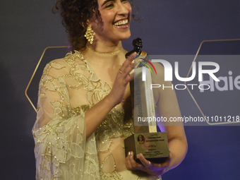 Bollywood actress Sanya Malhotra is posing for a photoshoot while holding an award in her hand during a red carpet event of the 'Dadasaheb P...