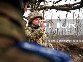 A serviceman from the 65th Separate Mechanized Brigade of the Land Forces of the Armed Forces of Ukraine is drinking water from a plastic bo...
