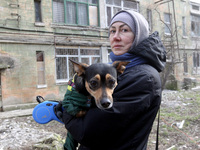A woman is holding a dog near a block of flats that was hit by a Russian Shahed drone during an overnight attack in Dnipro, Ukraine, on Febr...