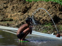 An indian boy takes bath to cool off in a municipal water pipe line, during a hot day in Allahabad on March 11,2016.In India, with climate c...