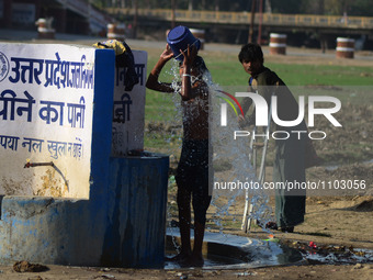 An indian man takes bath to cool off in a municipal drinking water pipe line, during a hot day in Allahabad on March 11,2016.In India, with...