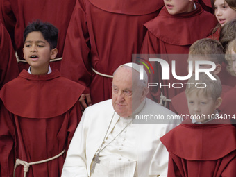 Pope Francis is posing for photos with the young members of a chorus at the end of his weekly general audience in the Paul VI Hall at the Va...