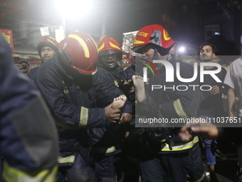 Firefighters are carrying an injured person during rescue operations following a fire in a commercial building that has killed at least 43 p...