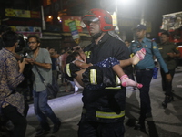 A firefighter is carrying an injured person during rescue operations following a fire in a commercial building in Dhaka, Bangladesh, on Febr...