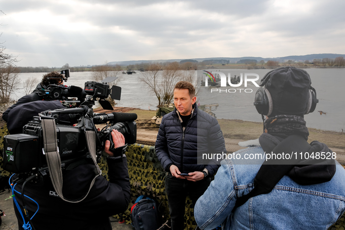 Journalist record live news as servicemen exercise ability to cross armored vehicles through Vistula river on ferries during NATO's  Dragon-...