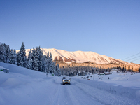 A passenger car is plying on a snow-covered road after a day of a snowstorm at the Gulmarg Ski Resort in the Baramulla district, Indian Admi...