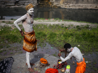 Naga Babas, known as Naked Hindu saints, are smearing ashes over each other's bodies after taking a bath on the embankments of the Bagmati R...