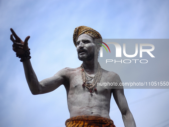 A Naga Baba, also known as a Naked Hindu saint, is gesturing while smearing ashes over his body after taking a bath on the embankments of th...