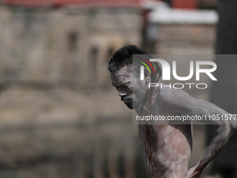 A Naga Baba, or Naked holy saint, is smearing ashes over his body on the embankments of the Bagmati River next to Pashupatinath Temple in Ka...