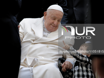 Pope Francis is smiling at a child at the end of his weekly general audience in St. Peter's Square at the Vatican, on March 6, 2024. (