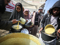 Displaced Palestinians are receiving cooked food rations at a donation point in Deir al-Balah in the central Gaza Strip, on March 6, 2024, a...