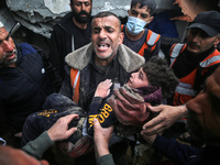 A civil defense member is carrying a child after recovering him from under the rubble of a house in Deir al-Balah in the central Gaza Strip,...