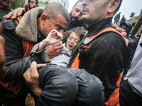 A civil defense member is carrying a child after recovering him from under the rubble of a house in Deir al-Balah in the central Gaza Strip,...