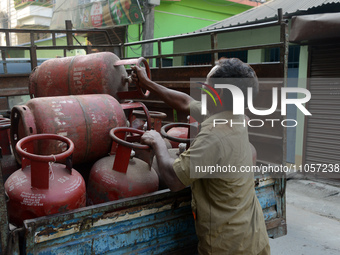 An employee is unloading cooking gas LPG cylinders from a vehicle to supply to houses in Siliguri, India, on March 8, 2024. India's Prime Mi...