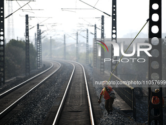 An overhead contact line worker at the Nanchang power supply section of China Southern Railway is hanging the ground wire at the Ruichang se...