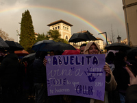 A woman is holding a banner that reads 'Granny, I came to shout everything they made you silence', under the rain and the rainbow during the...