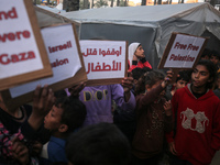 Displaced Palestinian children are raising banners during a march in Deir al-Balah in the central Gaza Strip, protesting against the ongoing...