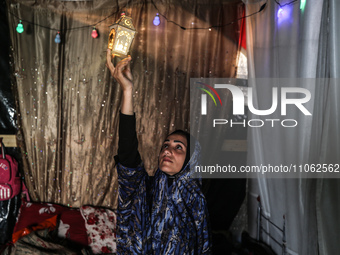 A displaced Palestinian woman is decorating her tent with Ramadan decorations in Deir al-Balah, in the central Gaza Strip, on March 9, 2024,...