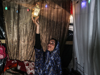 A displaced Palestinian woman is decorating her tent with Ramadan decorations in Deir al-Balah, in the central Gaza Strip, on March 9, 2024,...