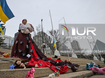 EDMONTON, CANADA - MARCH 9, 2024:
A protester, depicting a Ukrainian woman holding a young child surrounded by children's toys and blood, sy...