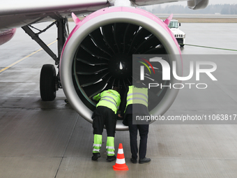 Workers are seen near a plane engine on the airport in Katowice, Poland on February 28, 2024. (