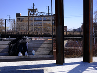 A person is shading themselves from the sun while sitting on a bench swing at the Rail Park trail on the reclaimed Reading Viaduct in Center...
