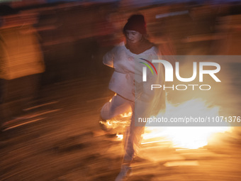 A young Iranian woman is jumping over a fire while participating in the annual ''Chahar Shanbeh Soori,'' also known as the fire festival, in...