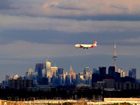 A plane is arriving at Toronto Pearson International Airport while the sun is setting on downtown Toronto. This view is captured from the Fi...