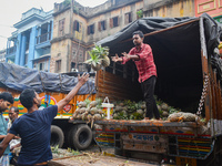A person is throwing a pineapple to load it into a truck inside a wholesale fruit market in Kolkata, India, on March 17, 2023. (
