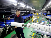A worker is producing textile foreign trade products on a workshop production line at a spandex company workshop in the Lianyungang Economic...
