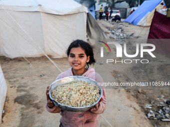A Palestinian girl is holding a bowl of rice before an iftar meal, the breaking of the fast, on the ninth day of the Muslim holy fasting mon...