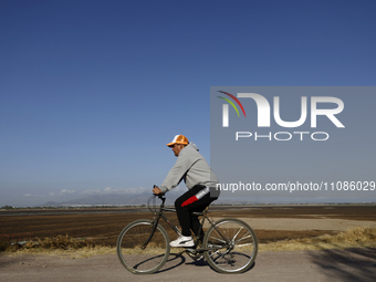 A cyclist is riding in front of the Laguna de Zumpango in the State of Mexico, which is completely dry, resulting in the accumulation of wee...