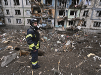 A rescuer is standing among the debris outside a multi-storey residential building that has been damaged as a result of a massive missile st...