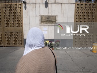 A woman is looking at flowers placed outside the Russian embassy in Tehran, Iran, on March 24, 2024, to honor the victims of a shooting at t...