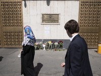 Two unidentified Russian diplomats are looking at flowers placed outside the Russian embassy in Tehran, Iran, on March 24, 2024, to honor th...