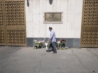 An Iranian man is walking past flowers placed outside the Russian embassy to honor the victims of a shooting at the Crocus City Hall concert...