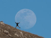 A man reaction in front of full worm moon is seen in L’Aquila, Italy, on march 23th, 2024. The Worm Moon is the traditional name for the ful...