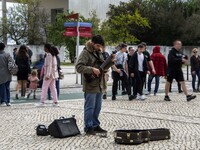 People are walking near a man who is playing a guitar along one of the walkways in Das Nacoes Park in the Oriente district, in Lisbon, Portu...