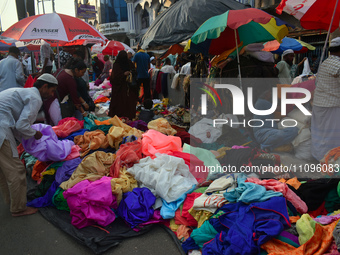 A person is selling colorful pieces of cloth for the upcoming Eid al-Fitr festival at a marketplace during the fasting month of Ramadan in K...