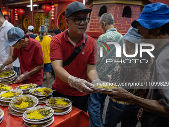 Indonesian Muslims are receiving food for iftar during the holy month of Ramadan at a temple in Jakarta, Indonesia, on March 26, 2024. As mi...
