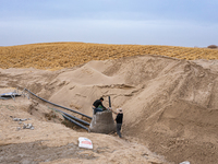 Construction workers are planting straw sand barriers in the desert at the construction site of an afforestation project along the Jinta Jin...