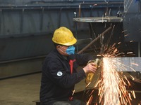 A worker is operating a self-developed water surface cleaning long-arm environmental protection ship at a shipping company's plant in Hangzh...
