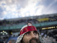 A man is wearing a Palestinian scarf and holding a portrait of Iran's Supreme Leader Ayatollah Ali Khamenei while participating in a religio...
