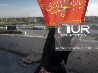 A young veiled Iranian woman is carrying a religious flag as she arrives at the Azadi (Freedom) Stadium to participate in a religious gather...