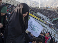 A veiled Iranian woman is carrying a religious flag as she arrives at the Azadi (Freedom) Stadium to participate in a religious gathering co...