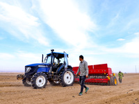 Farmers are using a Beidou navigation automatic driving tractor to sow, fertilize, mulch, and lay a drip irrigation belt for seeding wheat a...