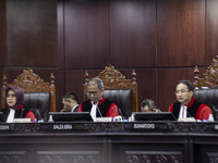 Chief Justice of the Indonesian Constitutional Court, Suhartoyo (C), along with other members of the judiciary, is reacting during the first...