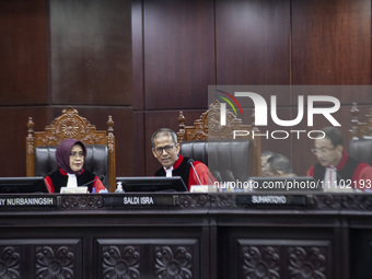 Chief Justice of the Indonesian Constitutional Court, Suhartoyo (C), along with other members of the judiciary, is reacting during the first...