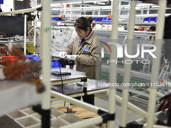 A worker is working on a production line of wiring harness products for a complete vehicle at a workshop of a technology company in Fuyang,...