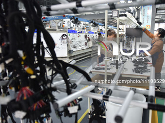 Workers are working on a production line of wiring harness products for complete vehicles at a workshop of a technology company in Fuyang, C...